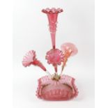 A cranberry glass epergne, having frilled and fluted vases and raised upon a further frilled