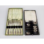 A box containing a cased set of six Arts & Crafts silver teaspoons, each having coloured cabochon