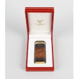 A Must de Cartier lighter, of rounded oblong form, having lacquered body simulating burr wood with