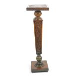 A carved and painted torchere, having a square pedestal top with circular panel and carved