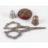 A pair of silver mounted sewing scissors having scrolled handles, plus two silver thimbles and a