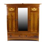 An Art Nouveau inlaid mahogany triple wardrobe, having a central mirrored door flanked by two