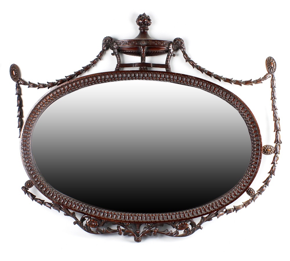 An Adam-style mahogany wall mirror, having a bevelled oval mirror plate within a stiff leaf border