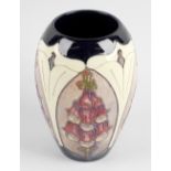 A Walter Moorcroft Foxglove pattern vase, of baluster form with tube lined decoration on a dark blue