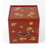 A Japanese lacquered table cabinet, of square form having sparse leaf decoration upon a red