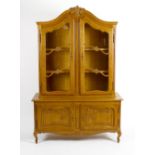 A reproduction oak display cabinet. The upper section with carved scrolled pediment above twin