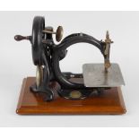 A Wilcox & Gibbs table top sewing machine, raised on wooden plinth, 10 (25.5cm). In used and worn