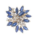 A diamond and sapphire floral cluster ring. Designed as a series of single-cut diamond curved lines,