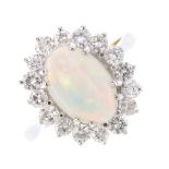 An opal and diamond cluster ring. The oval opal cabochon, within a brilliant-cut diamond surround.