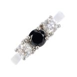 A platinum, diamond and gem-set three-stone ring. The circular-shape black gem, with brilliant-cut