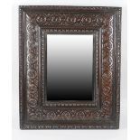 An oak framed wall mirror, the bevelled edged mirror of rectangular form, with conforming carved