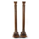 A pair of carved walnut Corinthian columns, each having a moulded waisted square top over foliage-