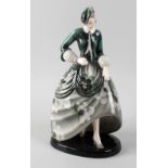 A Goldscheider figurine, modelled as a young woman in green floral dress, dress marked 'Claire