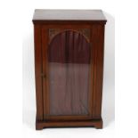 A late 19th century carved oak music cabinet, the rectangular top over arch-glazed door with