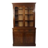 A late Victorian carved mahogany bookcase cabinet. The upper stage having a moulded dentil cornice