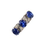 A sapphire three-stone and diamond ring. The oval-shape sapphire line, with vari-cut diamond