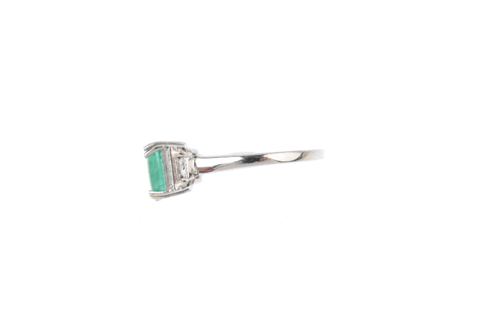 An emerald and diamond ring. The oval-shape emerald, with brilliant-cut diamond stepped sides. - Image 2 of 5