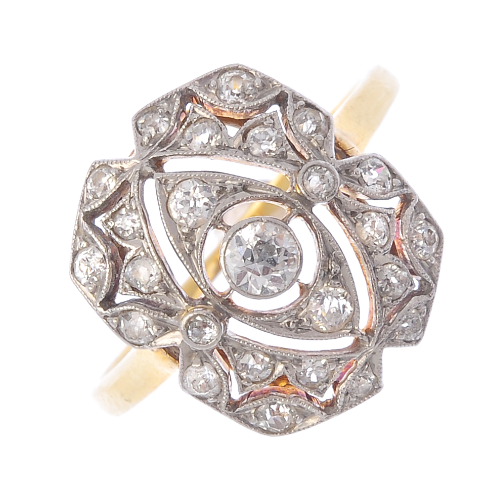 An Art Deco platinum and 18ct gold diamond ring. Of openwork design, the circular-cut diamond