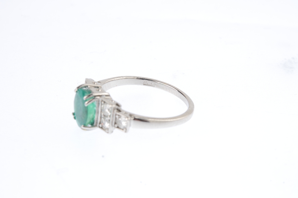 An emerald and diamond ring. The oval-shape emerald, with brilliant-cut diamond stepped sides. - Image 5 of 5