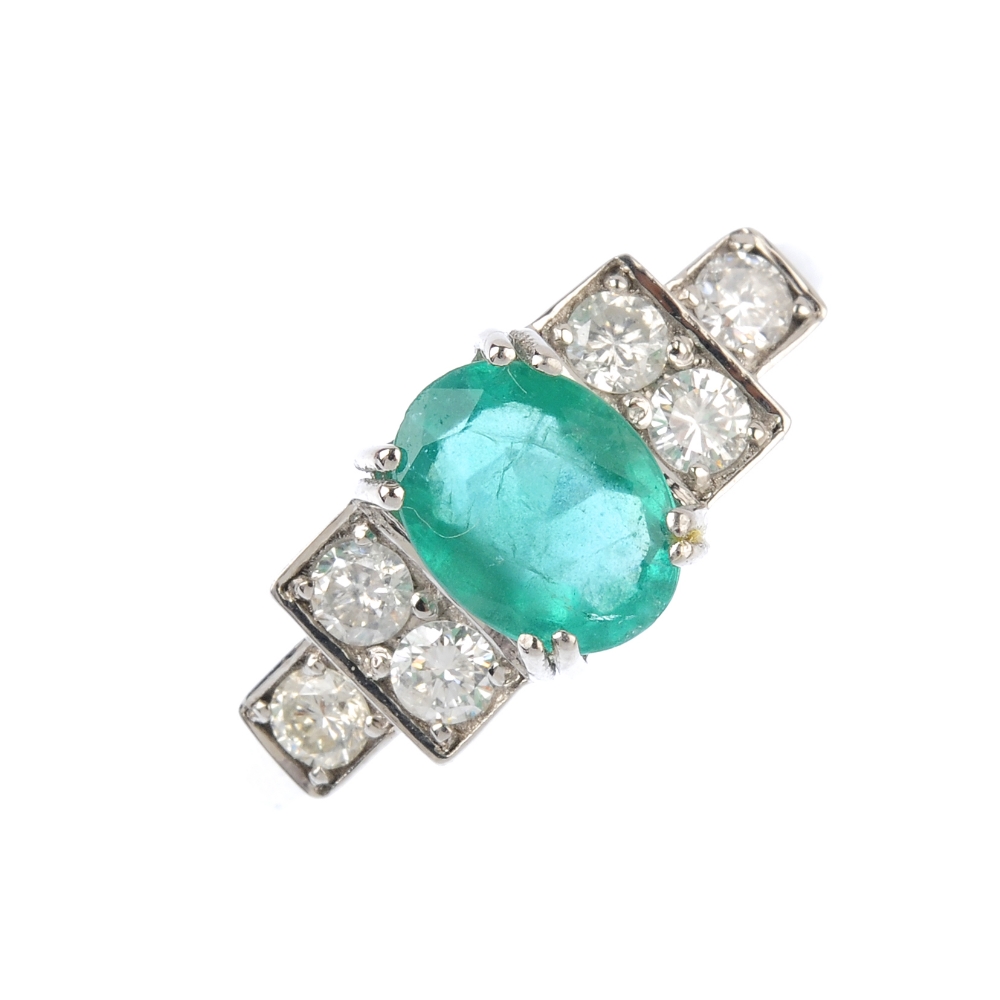 An emerald and diamond ring. The oval-shape emerald, with brilliant-cut diamond stepped sides.