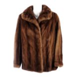 A three-quarter length demi-buff mink jacket with a stole. The jacket featuring a lapel collar, hook