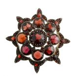 A garnet brooch. Of circular outline, with eight decorative points to the outer edge, the openwork