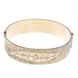 Four rolled gold bangles. To include a hinged bangle with textured pattern to one side and floral
