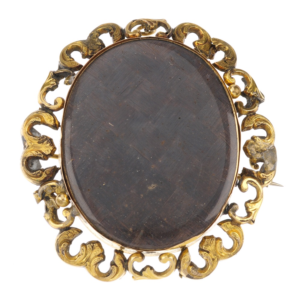 A late Victorian hand painted memorial brooch. Of oval outline, the glazed woven hair panel to the