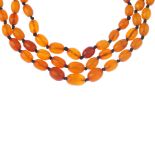 A natural amber bead necklace. The three rows of with a total of eighty-nine natural oval-shape