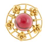 A garnet cabochon brooch. The brooch of concentric circular mount, with flower-shape accents, to the