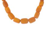 A natural amber bead necklace. Comprising a graduated row of twenty-three barrel-shape natural amber