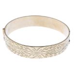 Four rolled gold bangles. One designed as an expanding bangle with diamond-cut star pattern, another