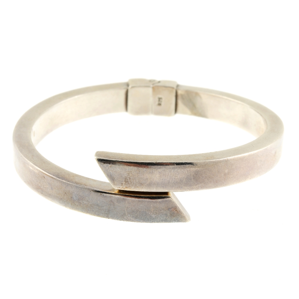 Two bangles. The first an asymmetric bangle with sprung hinge and angled terminals, the second a