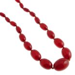 A bakelite bead necklace. Comprising a single row of fifty-three graduated oval-shape beads,