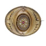 A memorial brooch. Of oval outline, central split pearl and red gem-set panel with marquise-shape