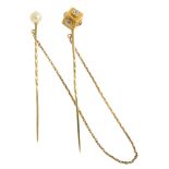 A double stickpin. One pin with a cultured pearl to the head, the other head designed as an engraved