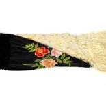 Two fringed shawls. The black shawl with a floral embroidered motif to one corner, knotted