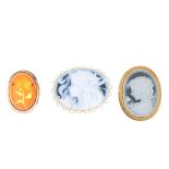 Three 9ct gold brooches. The first a resin cabochon of oval outline, with reverse carving of a