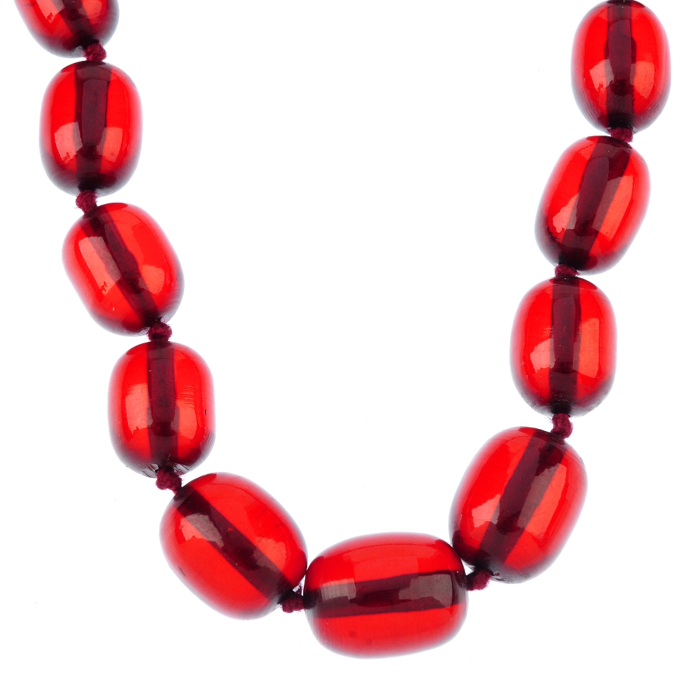 A red plastic bead necklace. Designed as forty-five barrel-shape beads of graduating size, measuring