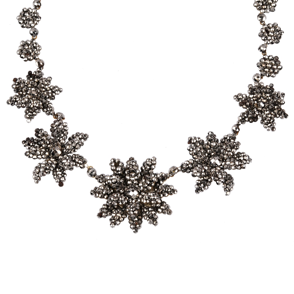 An early 19th century cut steel necklace. Designed as five cut steel flowers, with layered petal
