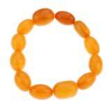 A natural amber bead bracelet. Comprising twelve oval-shape beads measuring 1.4 to 1.7cms, to an