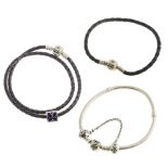 A selection of designer jewellery. To include two plaited leather Pandora bracelets, one black the