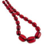 A red plastic bead necklace. Designed as thirty-four dark red translucent beads of barrel shape,