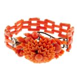 A carved coral bracelet. The bracelet designed as gate style links, to the carved central flower,