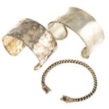 A selection of silver and white metal bangles. To include a buckle design two-tone bangle, stamped