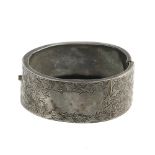 A late 19th century silver bangle. The hinged bangle with ivy-leaf engraving to the push-piece clasp