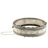 Two bangles. The first a silver, Victorian hinged bangle, with applied wirework borders to the