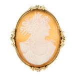 A shell cameo brooch. Of oval outline, the shell cameo carved to depict a man in profile in