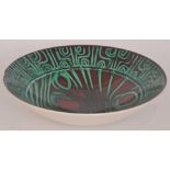 A Poole Pottery Delphis bowl decorated with copper green Aboriginal motifs against a dark red