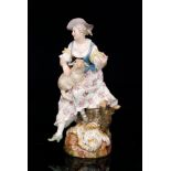 A 19th Century Meissen figure modelled as a shepherdess perched upon a gnarled branch holding a